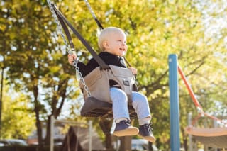 Sport mit Kindern | Baby schaukelt draußen in einer Babyschaukel