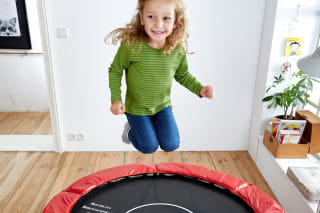 Sport mit Kindern | Mädchen hüpft auf Trampolin im Zimmer