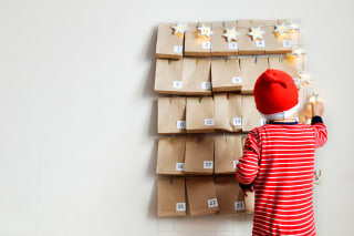 Adventskalender basteln | Kind steht mit Nikolausmütze vor dem Adventskalender