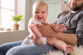 Baby zum Lachen bringen | Baby sitzt auf Schoss von Vater und lacht