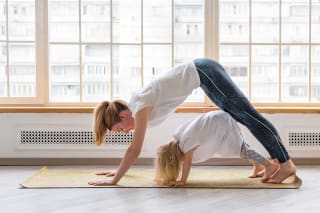 Entspannungsübungen für Kinder | Junge Mutter macht Yoga Hund Asana-Pose