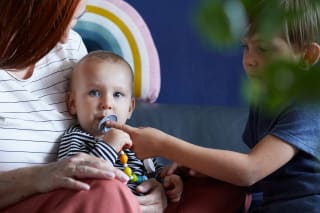 Geschwisterliebe | Mutter mit 2 Kinder kleines Geschwister sitzt vor der Mutter