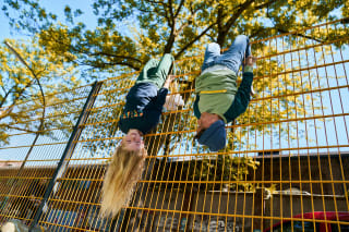 Glückliche Kindheit | Kinder hängen kopfüber am Gartenzaun ab