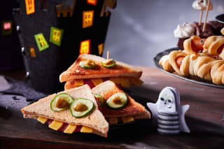 Halloween Rezepte | Toastecken mit Gurkenaugen und Käse-Zähnen auf dem Tisch