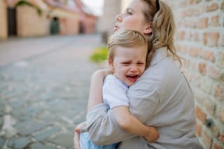 Kind weint | Kind liegt weinend in dem Arm von der Mutter