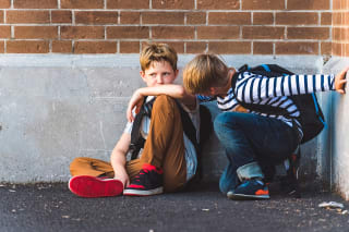 Kind hat keine Freunde | Zwei Jungs sitzen an einer Mauer gelehnt am Boden