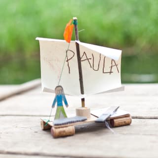 Kinderspiele selber machen | Floß aus Korken und Ästen, mit Papiersegel mit Aufschrift, Paula und Papp-Figur-Junge