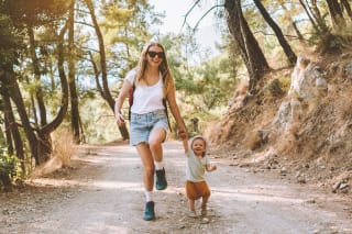 Urlaub mit Baby | Mama und Baby laufen hüpfend einen Waldweg entlang