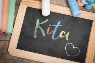 Kita Gebühren, Kindergarten Kosten | Auf einer Schiefertafel steht mit bunter Kreide Kita geschrieben