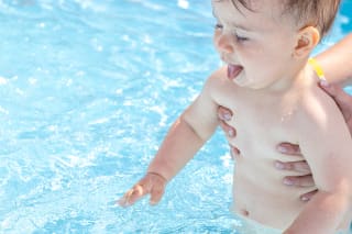  Frühkindliche Förderung | Baby wird ins Schwimmbecken gehalten 