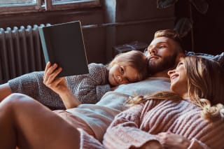 Angebrachte Bettgehzeiten | Mama, Papa und Tochter lesen zusammen ein Bilderbuch