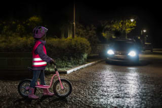 Reflektoren für Kinder | Kind mit Warnweste auf Fahrrad im Dunkeln