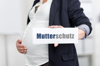 Checkliste | schwangere Frau hält Schild mit Schriftzug Mutterschutz