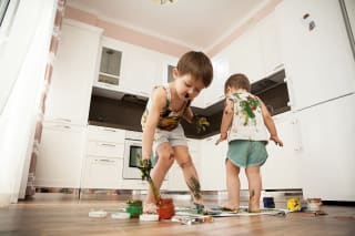 Erziehungsstile |  zwei Jungen malen mit Händen, Füßen und Pinsel auf Papier, am Küchenboden