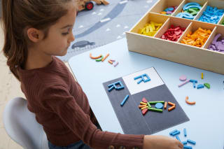 Fröbel - Alphabet | Mädchen hat ein R in blauen Holzstäben gelegt 