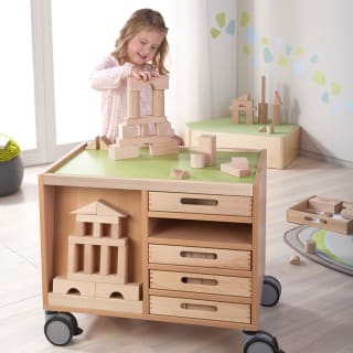 Fröbel - Bauen & Spielen | Mädchen stapelt Holzbausteine auf einem Rollwagen