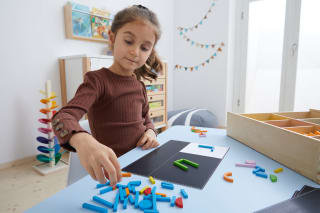 Fröbel - Alphabet | Mädchen legt ein U in grünen Holzstäben 