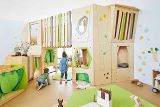 Geschäftsräume & Praxen | Indoor Spielplatz | zweistöckiger Indoorspielplatz aus Buchholzplatten mit Fenster, Zaun, Kuschelecke ausgelegt mit grünen Teppichen