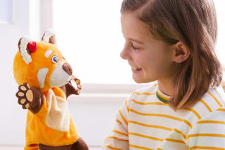 Ein Mädchen hält die Handpuppe Fay in der Hand und spricht mit ihr.