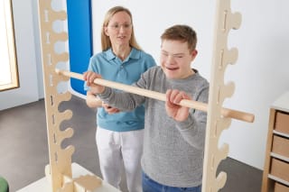 Ein Patient mit Behinderung eine Therapeutin an einem Manufit-Gerät.