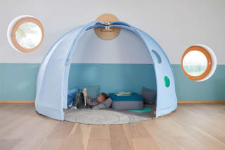 Ein Kind zieht sich in einem Therapieraum in eine ruhige Höhle zurück.