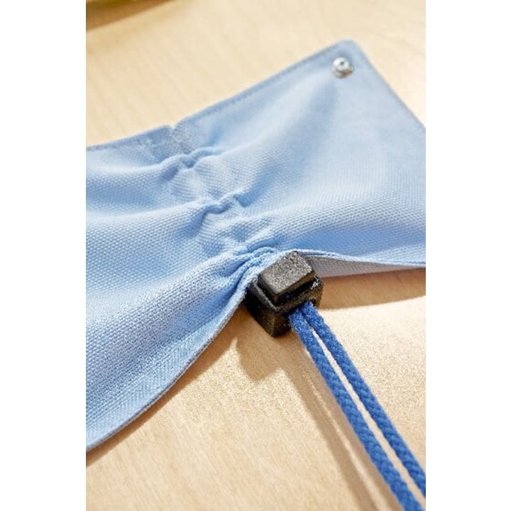 Nahaufnahme eines blauen Stoffes mit einer verstellbaren elastischen Schnur, die durch ein schwarzes Kunststoffschloss gezogen ist und auf einer hellen Holzfläche liegt.