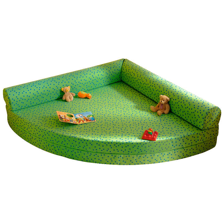 Eine grüne, L-förmige gepolsterte Spielmatte mit blauen Punkten, auf der ein Plüschbär, ein kleiner Spielzeuglastwagen, eine Spielzeuggiraffe, ein Spielzeuglöwe und ein aufgeschlagenes Kinderbuch liegen.