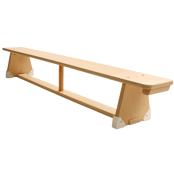 Eine lange Bank aus hellem Holz mit einer flachen Sitzfläche, zwei dreieckigen Endstützen und einer horizontalen Stützstange darunter. Die Bank hat ein einfaches Design und ist vor einem weißen Hintergrund abgebildet.