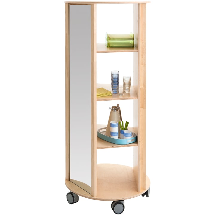Ein mobiles Regal aus hellem Holz mit einer verspiegelten Seite und drei Einlegeböden, auf denen bunte Tabletts, Gläser und eine Karaffe stehen, alles auf großen schwarzen Rollen.