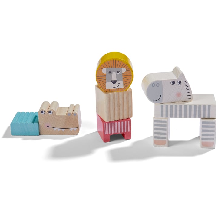 Drei Tierspielzeuge aus Holz, darunter ein blaues und beiges Krokodil, ein stapelbarer Löwe mit gelber Mähne und ein weißes Zebra mit grauen Streifen, die alle auf einem weißen Hintergrund stehen.