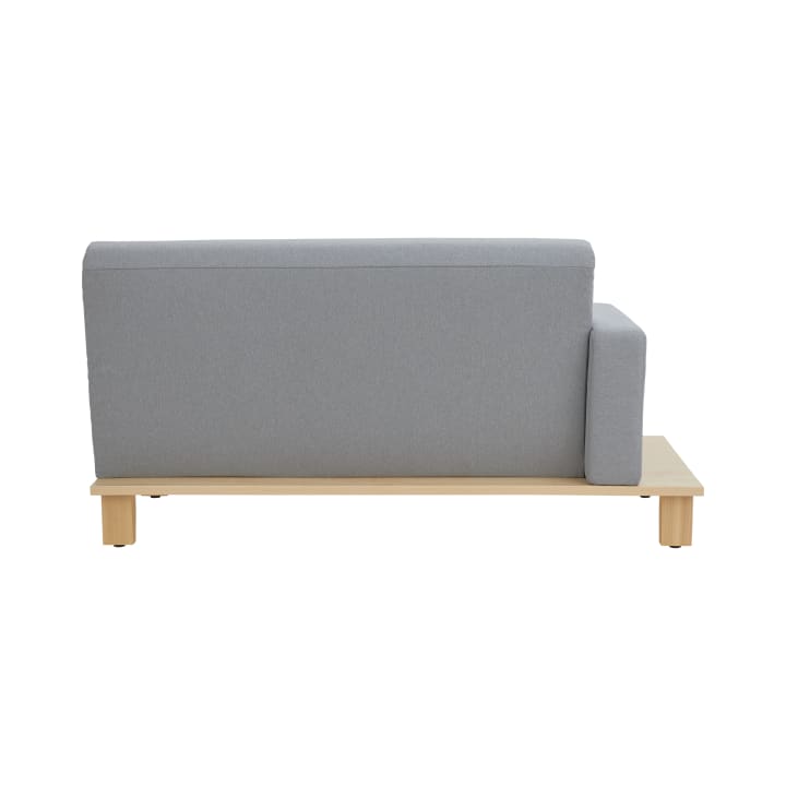 Ein hellgrau gepolstertes Sofa in der Seitenansicht mit einer Armlehne auf der rechten Seite, auf einem hellen Holzsockel mit vier quadratischen Beinen vor weißem Hintergrund.