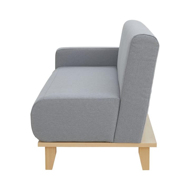 Ein modernes graues gepolstertes Sofa mit Holzgestell und ohne sichtbare Kissen, dargestellt von der Seite vor einem weißen Hintergrund.