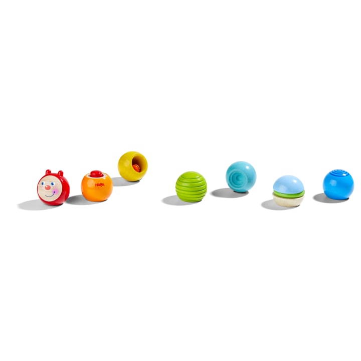 Sechs bunte, runde Holzspielzeuge sind in einer Reihe auf weißem Hintergrund angeordnet. Jedes Spielzeug hat eine andere Form und Farbe, darunter rot, orange, grün, blau und hellblau.