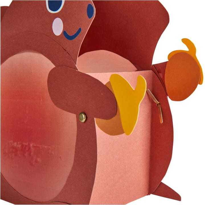 Nahaufnahme einer Pappschachtel, die wie ein Tier aussieht, mit braunem und rosa Papier, blauen und weißen Augen und gelben Papierfüßen und Händen, die mit Metallverschlüssen befestigt sind.