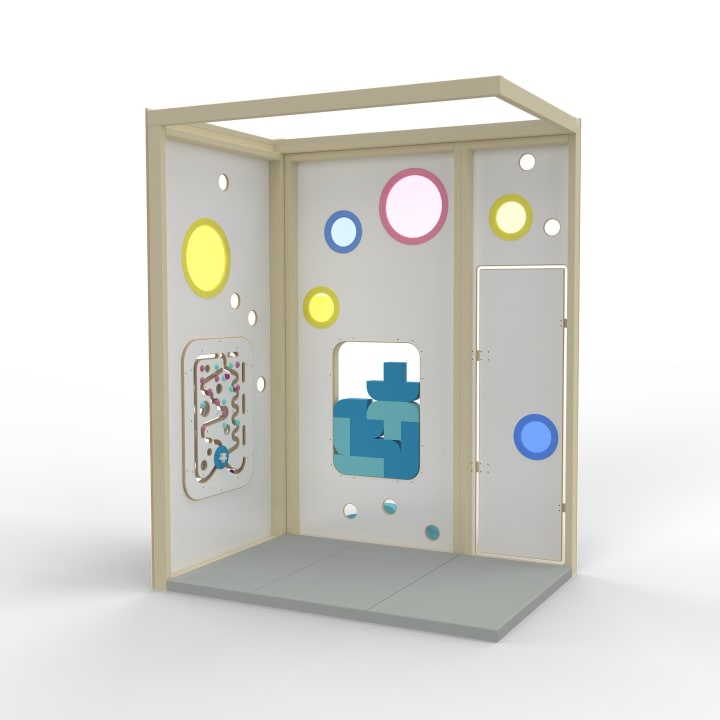 Eine dreiflügelige Spielstruktur mit einem Rahmen aus hellem Holz, weißen Paneelen mit kreisförmigen Ausschnitten in Gelb und Rosa, einem Spielbrett mit einem Labyrinth und einem blauen Blockpuzzle. Der Boden ist mit grauen gepolsterten Matten ausgelegt.