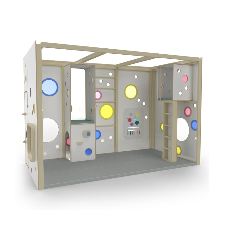 Eine rechteckige Indoor-Spielstruktur mit hellem Holzrahmen, grauem Boden, Wandausschnitten in verschiedenen Formen und Farben, einer kleinen Plattform mit Stufen, einer Kletterleiter und einer interaktiven Tafel.