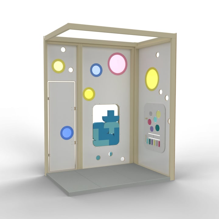 Ein kleines, offenes Spielgerüst mit runden, farbigen Fenstern, einer interaktiven Tafel mit farbigen Punkten und geometrischen blauen Formen, die hinter einem Ausschnitt sichtbar sind. Der Boden ist grau und der Rahmen ist aus hellem Holz.
