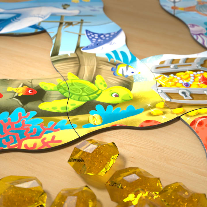 Eine Nahaufnahme eines farbenfrohen Meerespuzzles mit einer Schildkröte, Korallen, einer Schatztruhe und Fischen. Mehrere gelbe, edelsteinähnliche Spielsteine befinden sich auf der hölzernen Oberfläche nahe dem Rand des Puzzles.