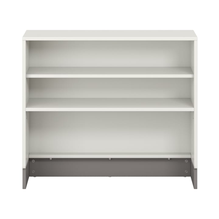Ein weißes Bücherregal mit drei Regalen, einer massiven Rückwand und einem kontrastierenden grauen Sockel, das leer vor einem unifarbenen Hintergrund gezeigt wird.