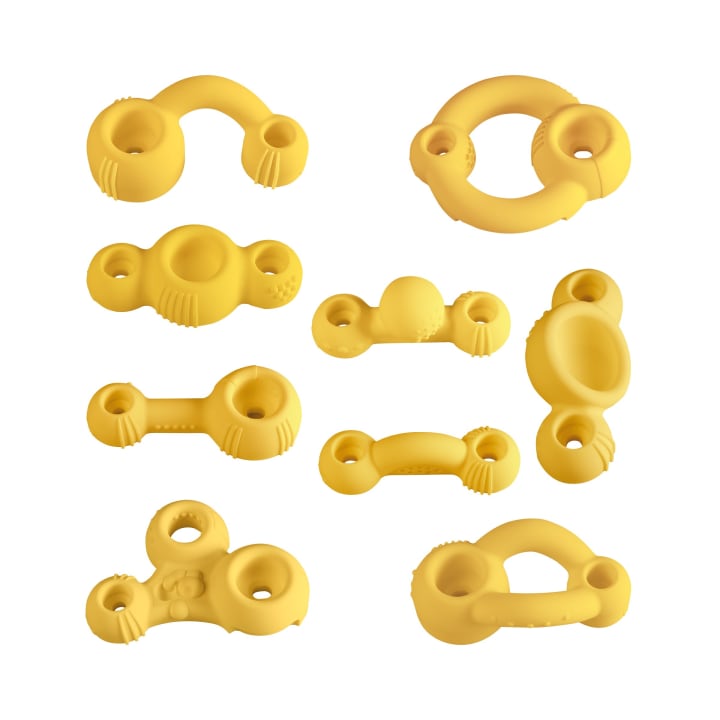 Neun gelbe Beißspielzeuge aus Gummi in verschiedenen runden Formen und Größen sind in einem Raster auf weißem Hintergrund angeordnet. Jedes Spielzeug hat mehrere Löcher, Rillen und strukturierte Bereiche, die zum Greifen und Kauen einladen.
