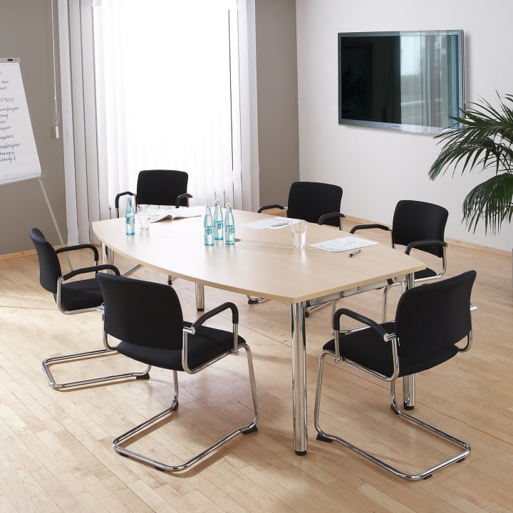 Ein moderner Konferenzraum mit einem Holztisch, sechs schwarzen Stühlen, Wasserflaschen, Gläsern, Notizblöcken, einem Whiteboard, einem an der Wand montierten Fernseher und einem großen Fenster mit vertikalen Jalousien. In der Ecke steht eine Topfpflanze.