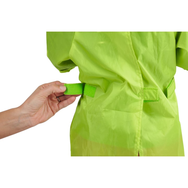 Eine Hand stellt einen grünen Klettverschluss an der Taille eines hellgrünen Kleidungsstücks ein (von hinten gesehen).