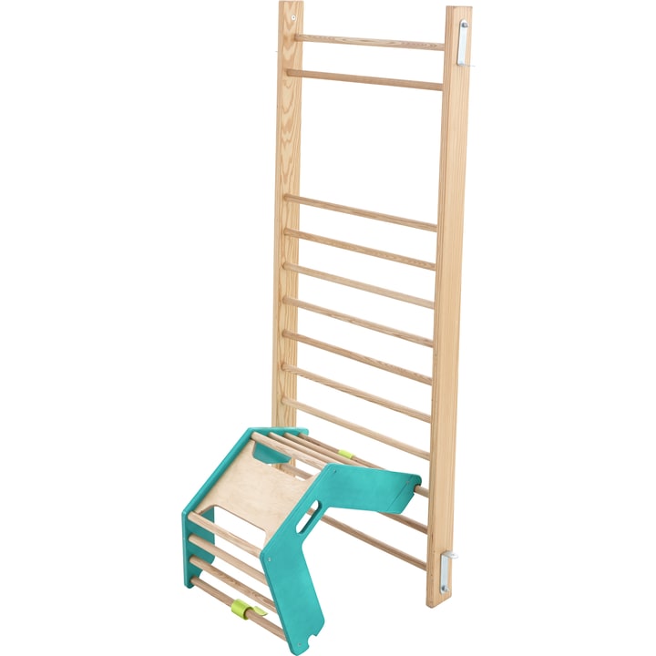 Eine hölzerne Kletterwand mit gleichmäßig verteilten horizontalen Sprossen ist aufrecht aufgestellt. Davor befindet sich eine separate Kletterstruktur aus Grün und Holz mit Griffen und horizontalen Stangen.