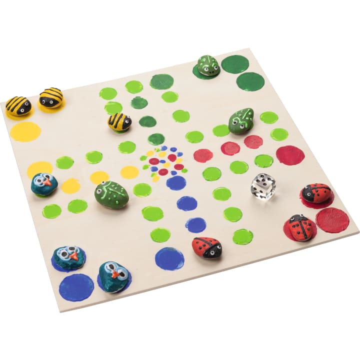 Ein handbemaltes Brettspiel mit farbigen Kreisen und bemalten Steinsplittern, die Bienen, Fröschen, Marienkäfern und blauen Vögeln ähneln, sowie zwei Würfeln. Das Spielbrett hat rote, gelbe, grüne und blaue Pfade.