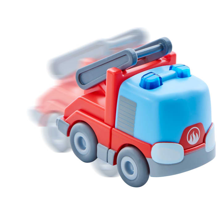 Ein Plastikspielzeug-Feuerwehrauto mit blauen Lichtern und einer roten und grauen Karosserie scheint sich schnell zu bewegen, mit einem Bewegungsunschärfe-Effekt dahinter auf einem weißen Hintergrund.