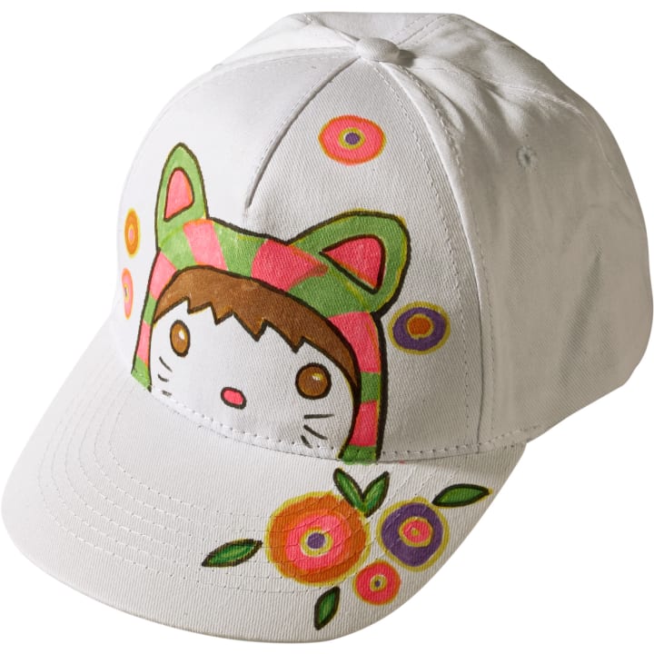 Eine weiße Baseballmütze mit einem Cartoon-Gesicht mit katzenartigen Ohren und bunten Blumen, hauptsächlich in Rosa-, Grün-, Orange- und Lila-Tönen, die auf der Vorderseite und dem Rand aufgedruckt sind.