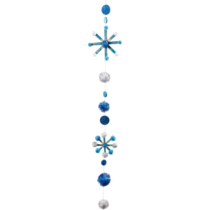 Eine vertikale Hängedekoration mit blauen und silbernen Glitzerkugeln, blauen und weißen Fuzzy Poms und zwei Sternenformen, die durch eine Schnur verbunden sind.