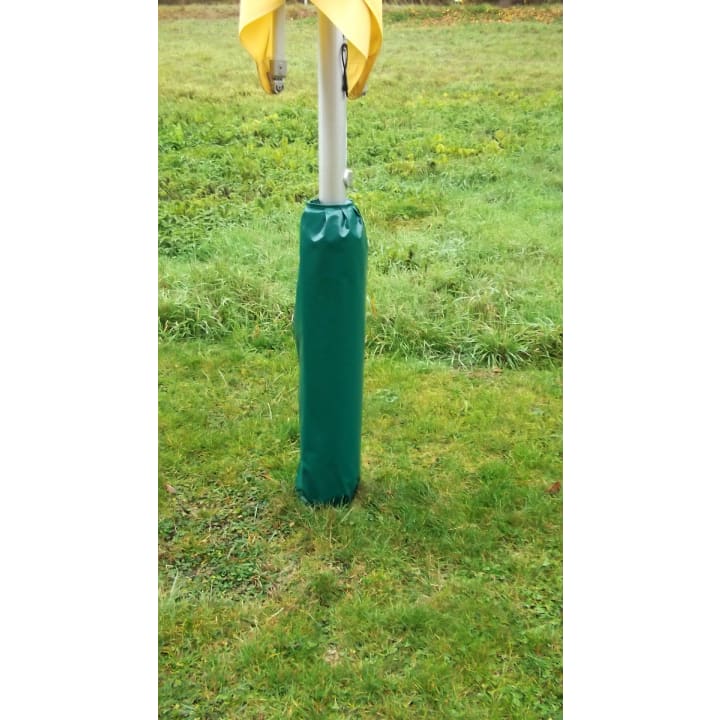 Ein gepolsterter grüner Bezug ist um die Basis eines vertikalen weißen Pfahls gewickelt, an dessen Spitze ein gelber Stoff drapiert ist. Die Stange steht auf einem grasbewachsenen Feld.