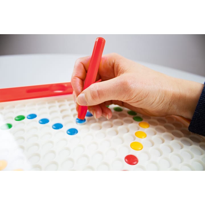 Eine Hand setzt einen blauen runden Stift auf eine weiße Tafel mit gleichmäßig verteilten Löchern. Andere bunte Stifte, darunter gelbe, grüne und rote, sind bereits auf dem Brett positioniert.