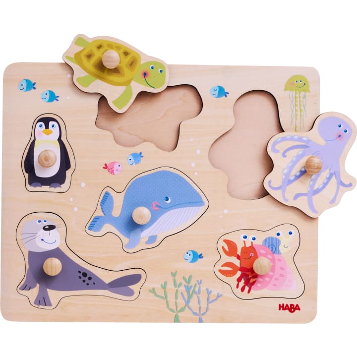 Ein hölzernes Puzzlebrett mit Abbildungen eines Pinguins, eines Wals, einer Robbe, einer Schildkröte und eines Oktopus. Die Teile der Schildkröte und des Oktopus werden angehoben und zeigen ihre leeren Steckplätze.